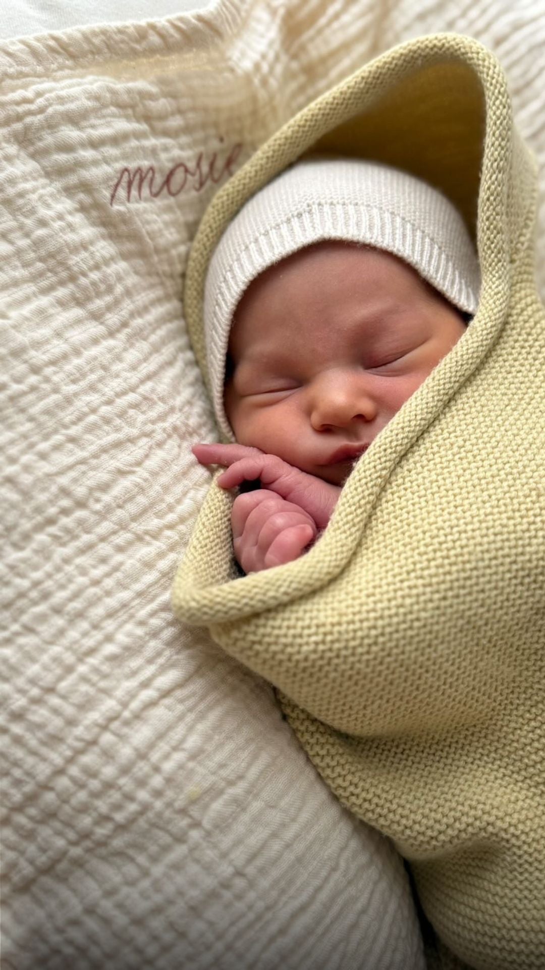 Sleeping newborn baby wrapped in a yellow blanket on a soft muslin cloth